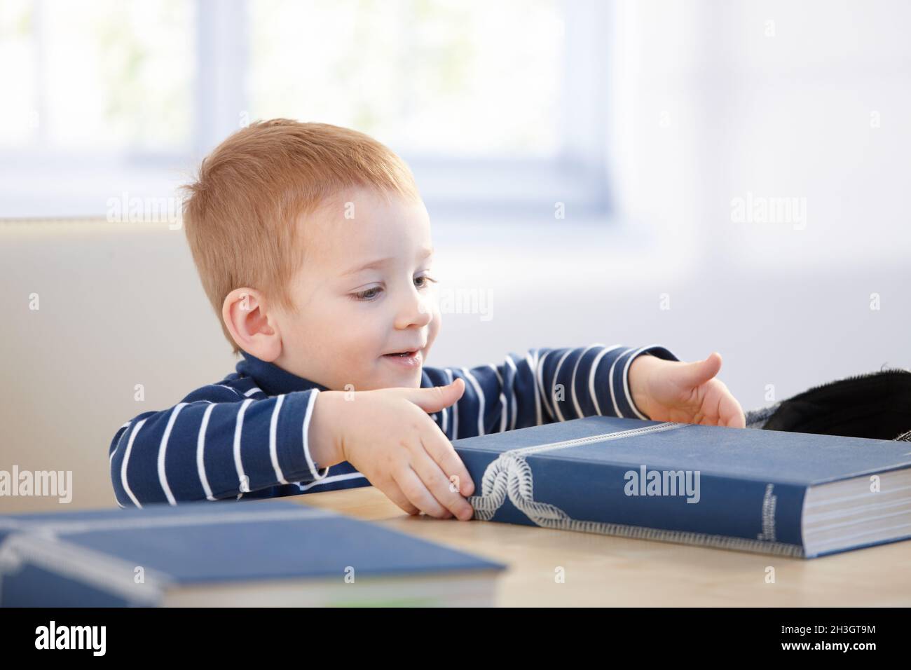 Ginger-haired little boy with encyclopedia smiling Stock Photo