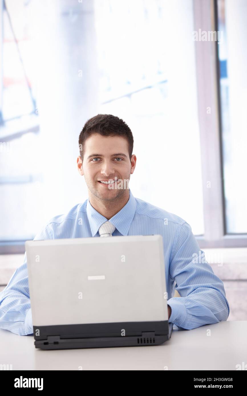 Confident businessman working on laptop smiling Stock Photo