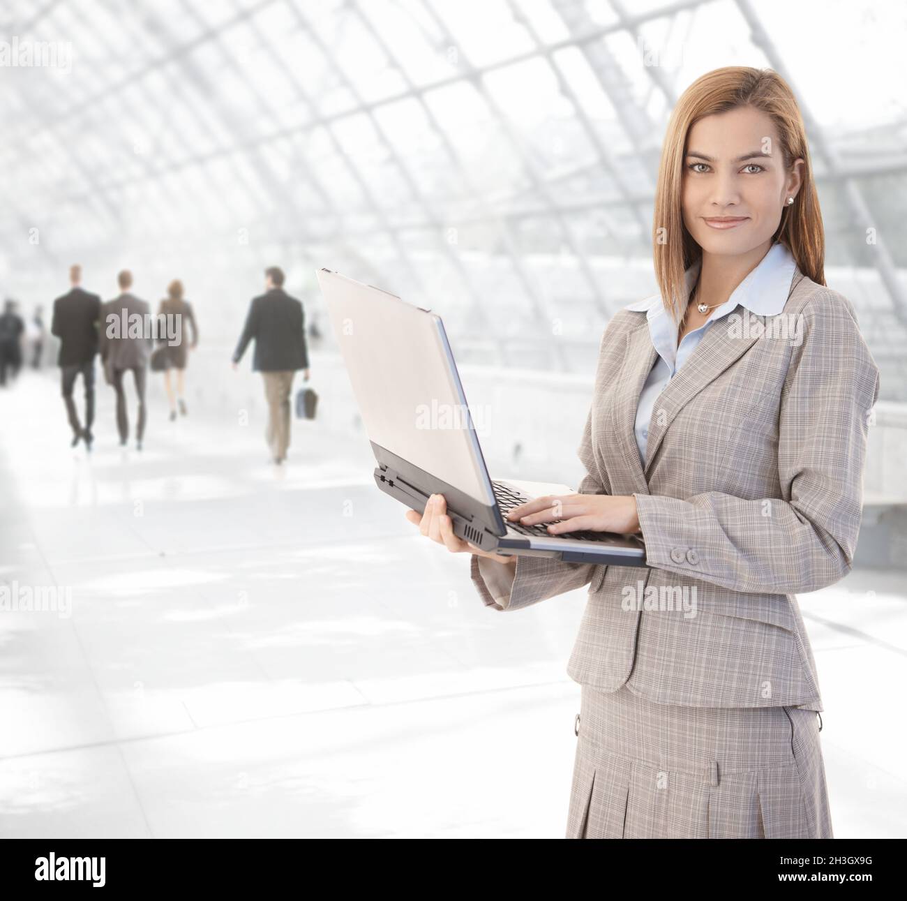Attractive businesswoman using laptop at passage Stock Photo