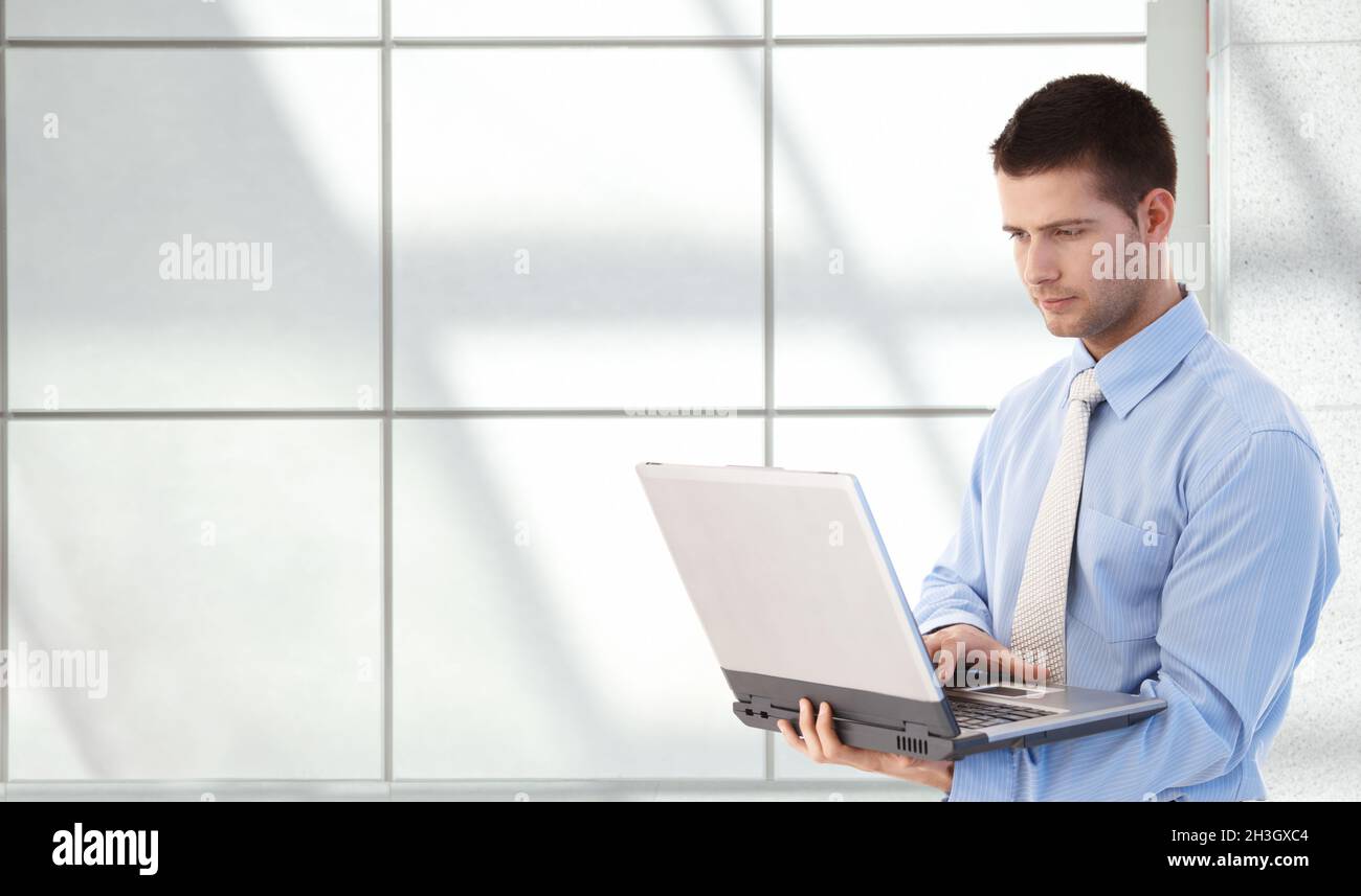 Young professional using laptop in office lobby Stock Photo