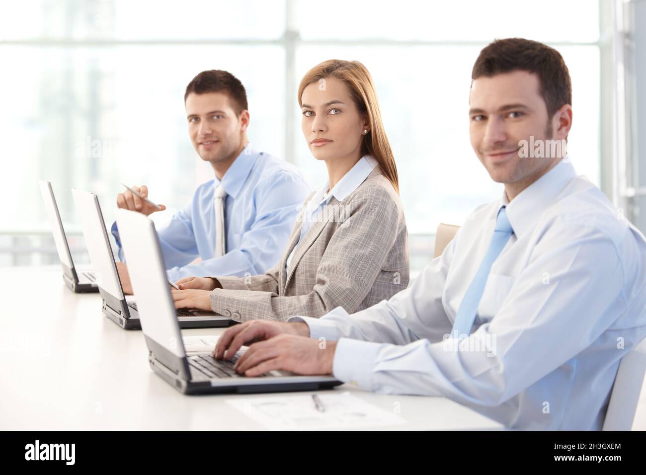 Young businesspeople working on laptop smiling Stock Photo