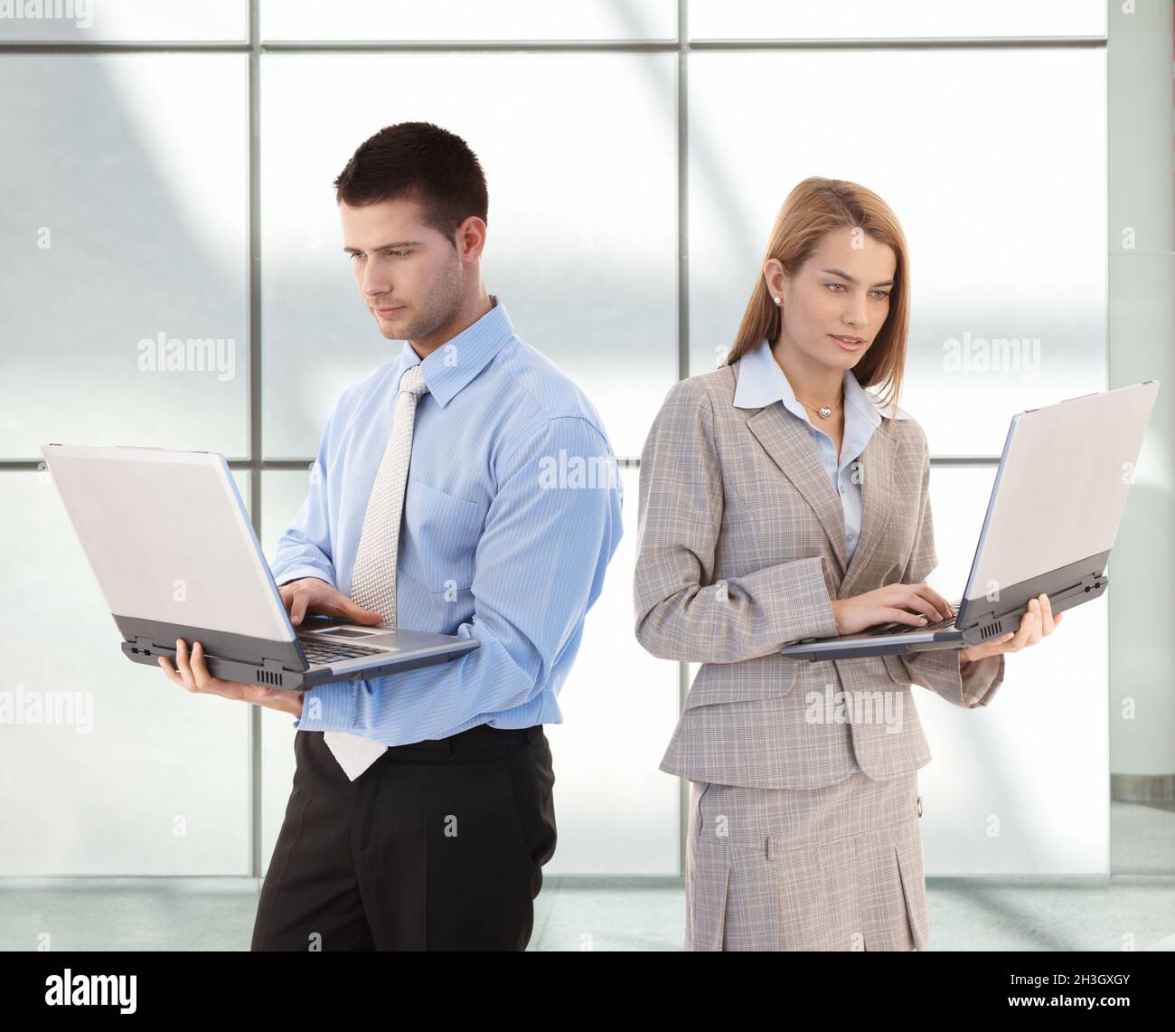 Young businesspeople using laptop in office lobby Stock Photo