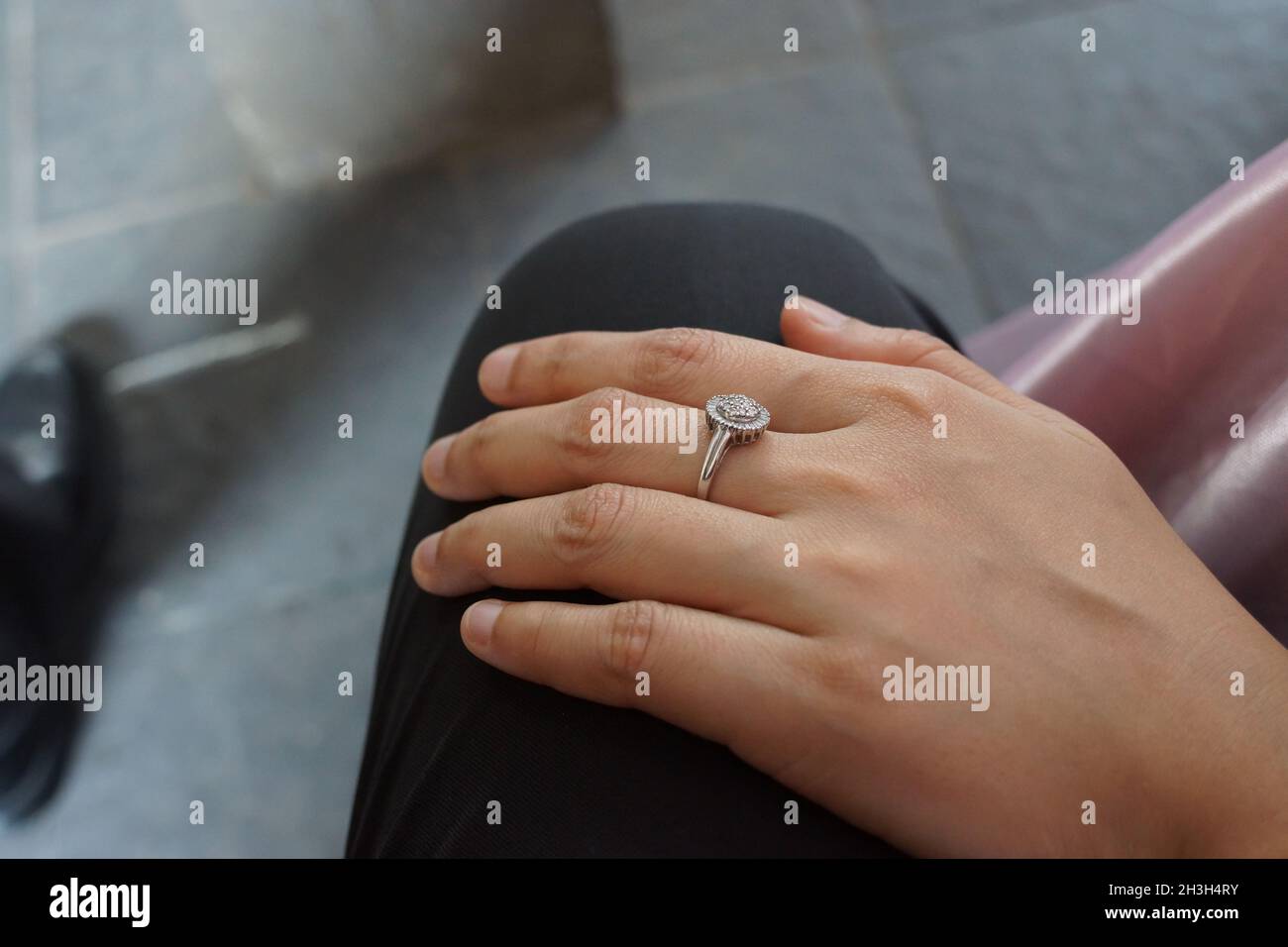 Close up wife hand with silver diamond ring on husband lap with bokeh background. Love, marriage, engagement, happiness, family and romance concept. Stock Photo