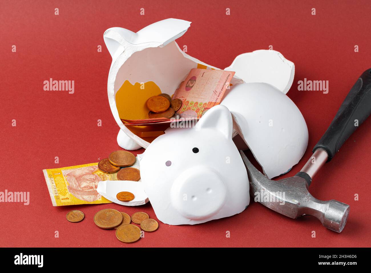 Broken piggy bank with ukrainian money notes and coins. Decline in