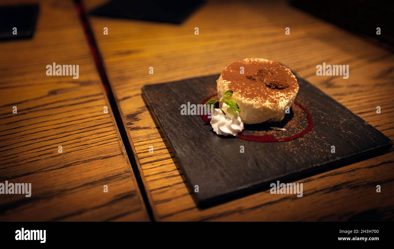 A plate, decorated with whipped cream and mint leaves, for presenting the dessert course of Italian tiramisu in Hiroshima, Japan. Stock Photo
