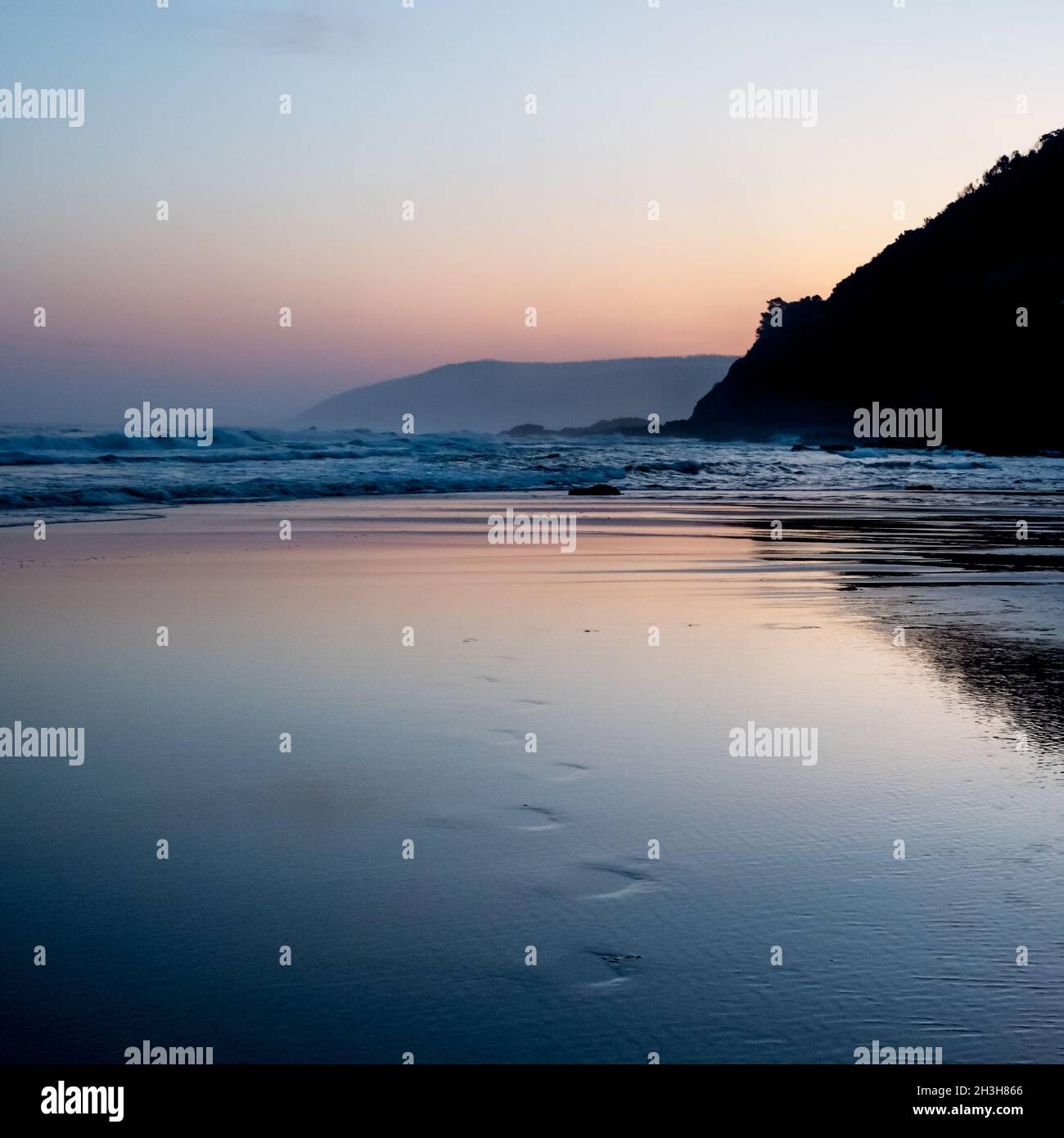 Footprints in sand leading from the sea.  Just after sunset along Australia's Great Ocean Road near Lorne, Victoria Stock Photo
