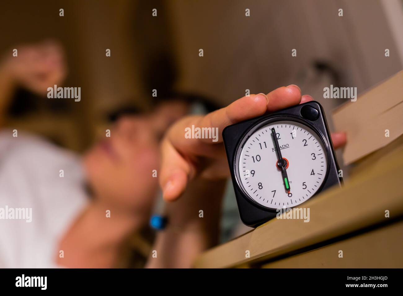 Berlin, Germany. 27th Oct, 2021. A woman switches off an alarm clock, which  points to 6 o'clock (posed scene). On 31.10.2021 the summer time (CEST)  ends, it is again Central European Standard
