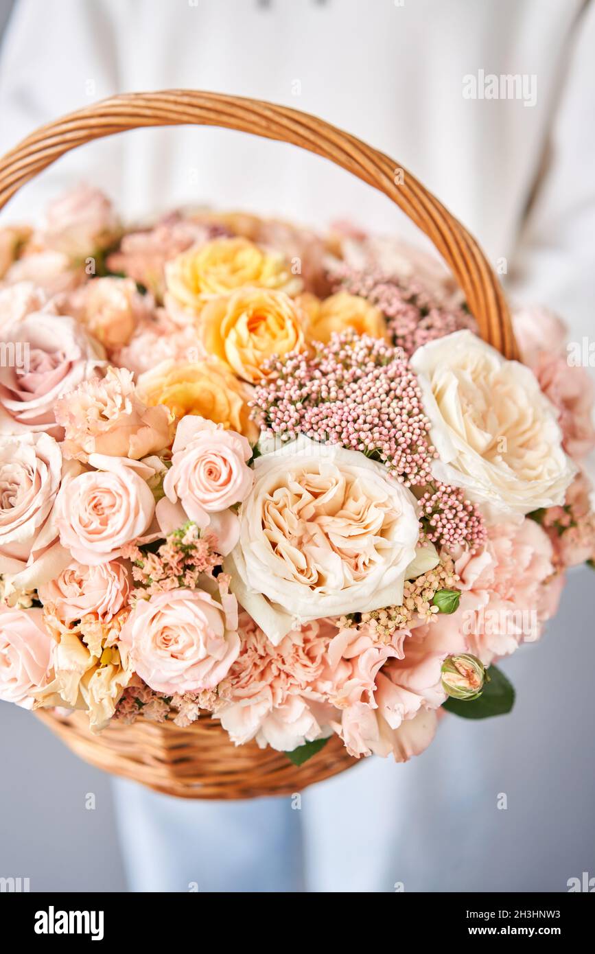 Flower arrangement in Wicker basket. Beautiful bouquet of mixed flowers in woman hand. Handsome fresh bouquet. Small flower shop and Flowers delivery. Stock Photo