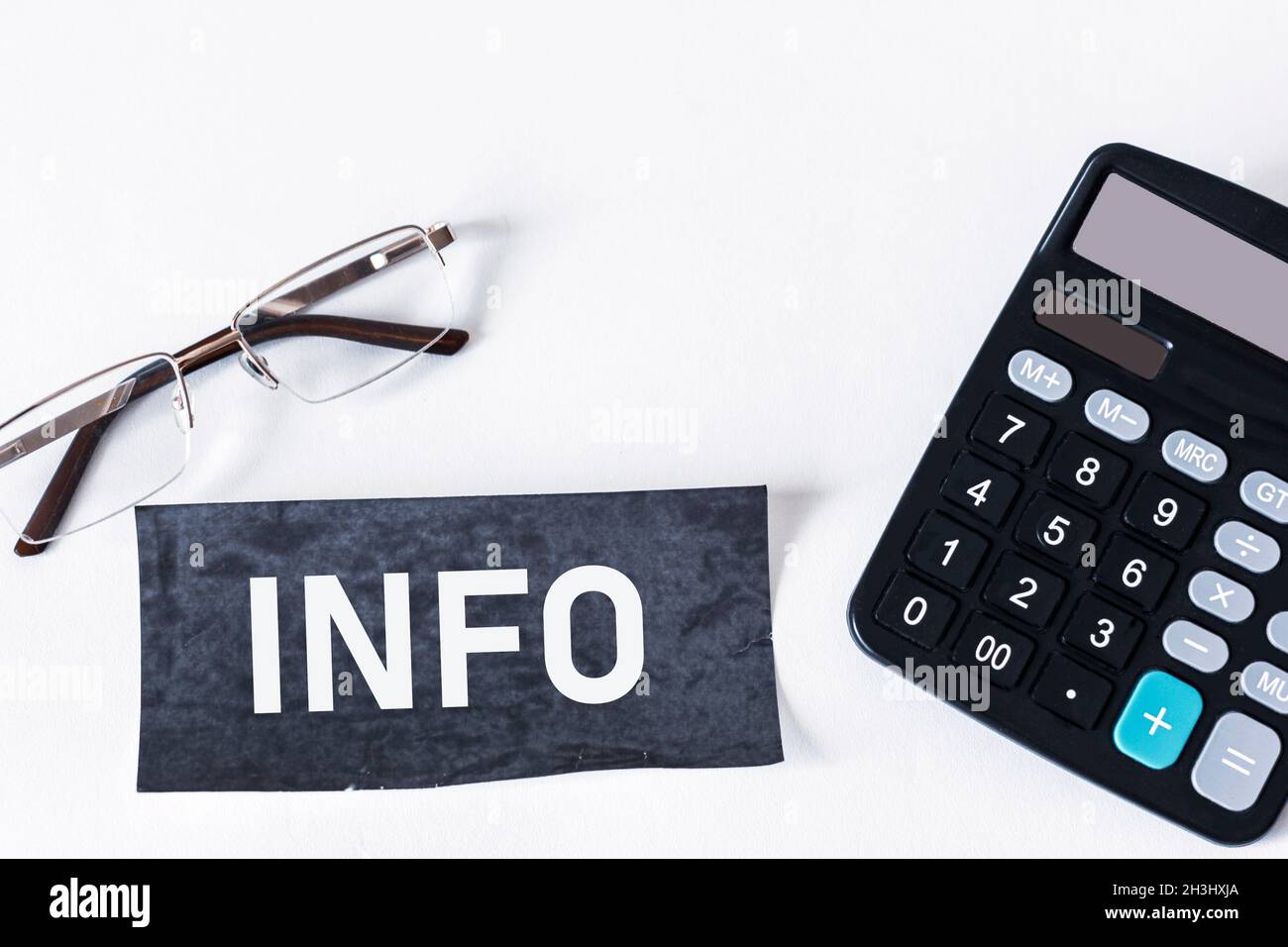 On a white background calculator, glasses and a black sticker with the text INFO Stock Photo