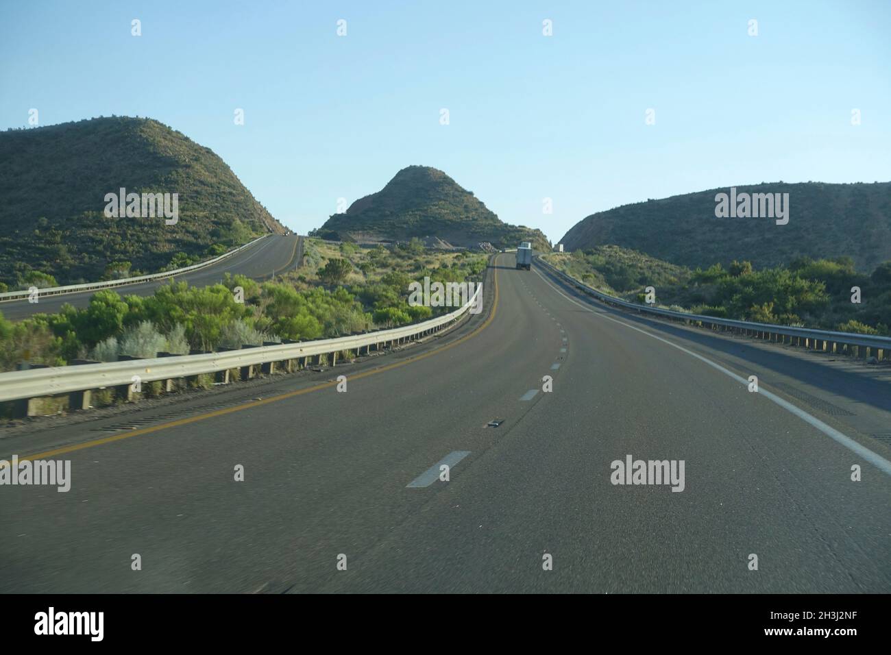 Empty highway winding through beautiful green rolling hills. Stock Photo
