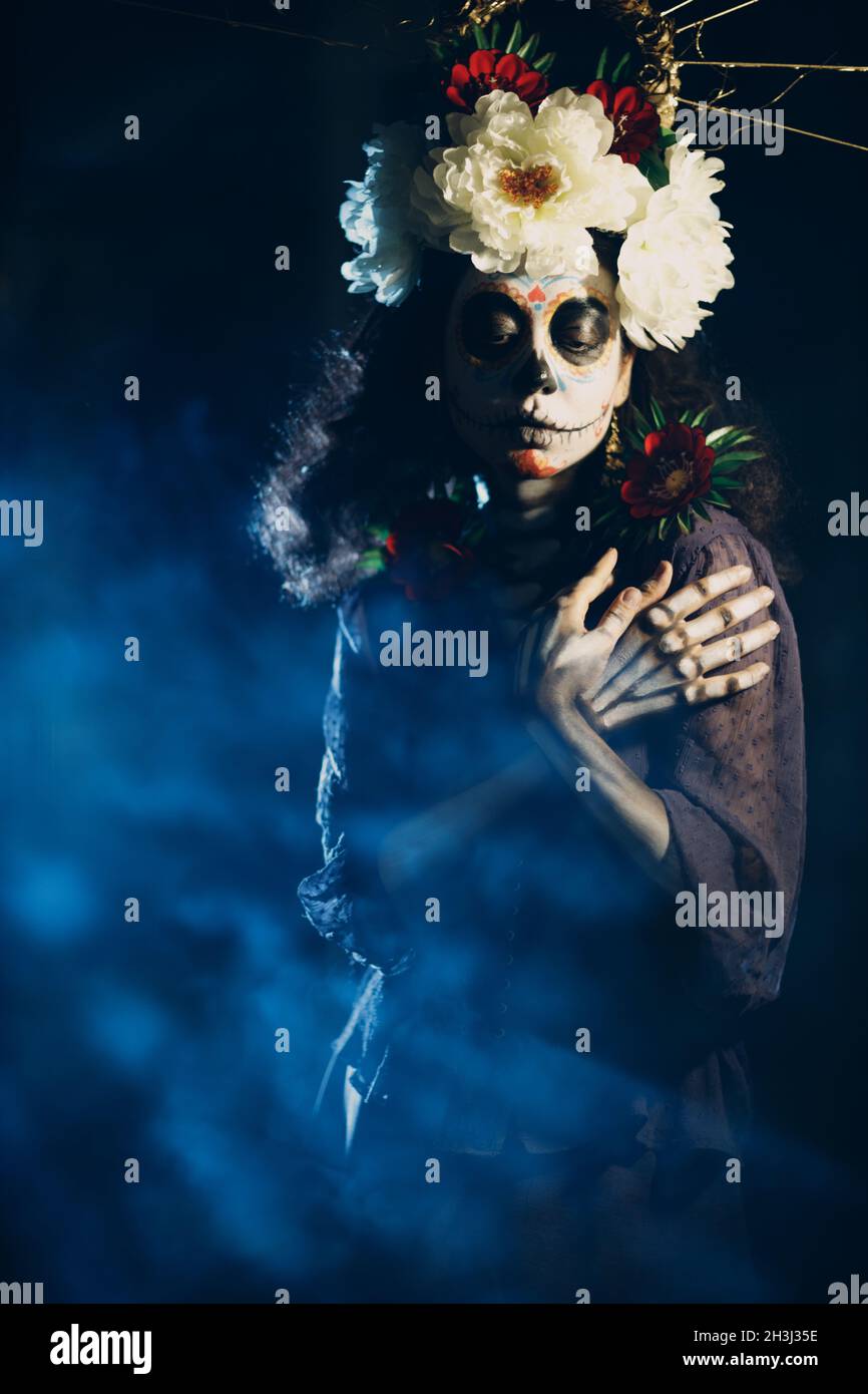 Woman with mexican skull halloween makeup on face. Day of the dead aka Dia de los Muertos and halloween concept. Stock Photo