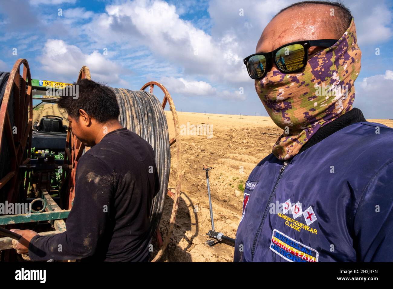 Labourers from Thailand working with machinery on the Alumim Kubbutz in the negev desert, southern Israel Stock Photo