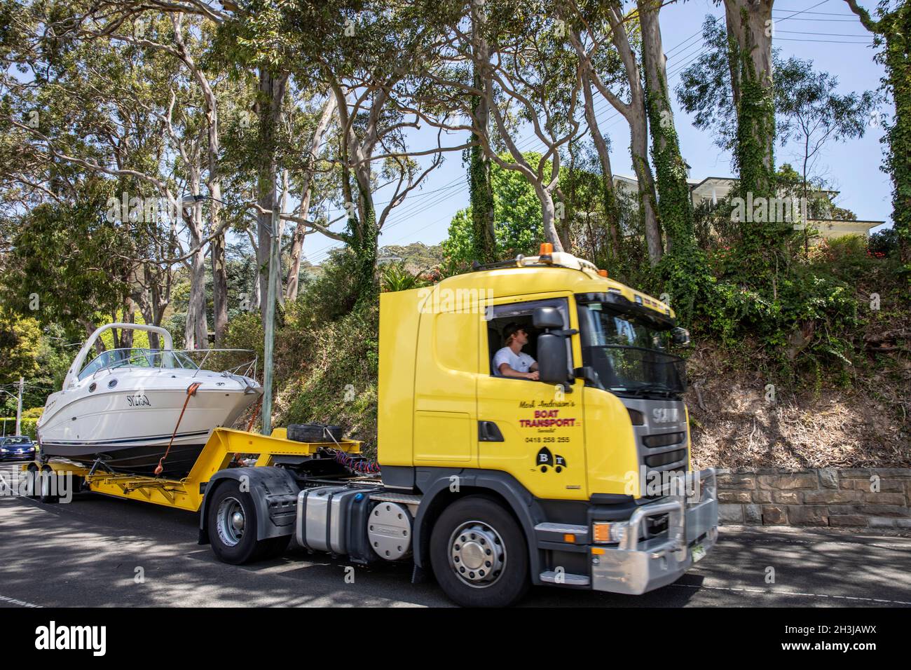 Lorry driver transporting a large cruiser boat on his truck to a marina