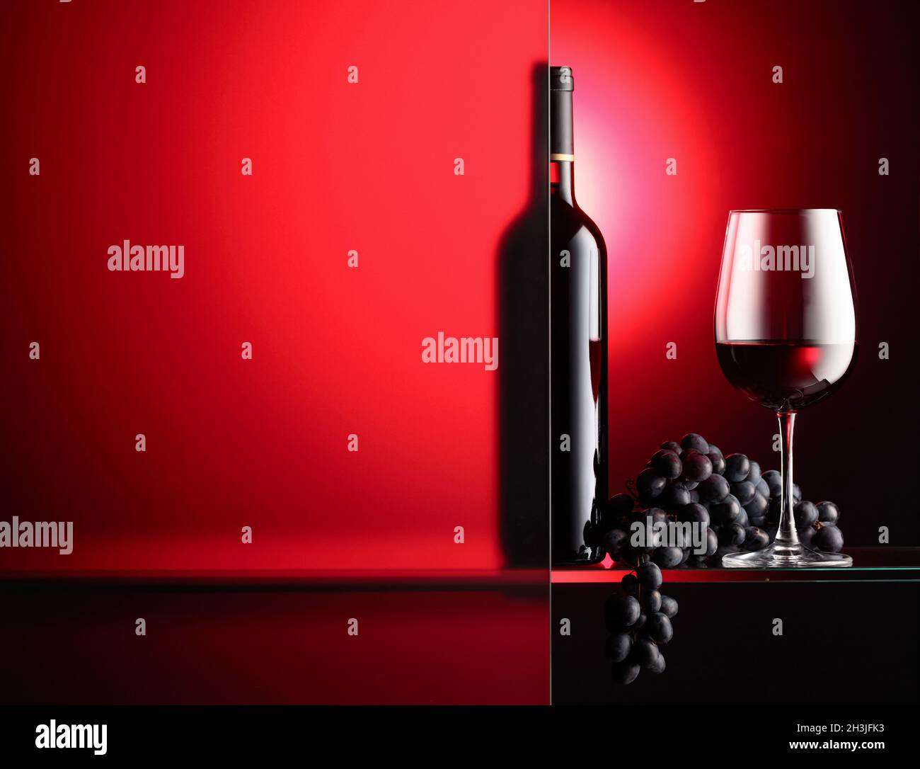 Bottle and a glass of red wine with a bunch of blue grapes. The still ...