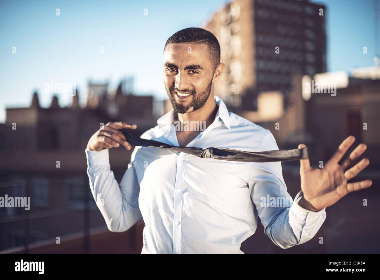 Confident attractive Arab businessman undressing Stock Photo