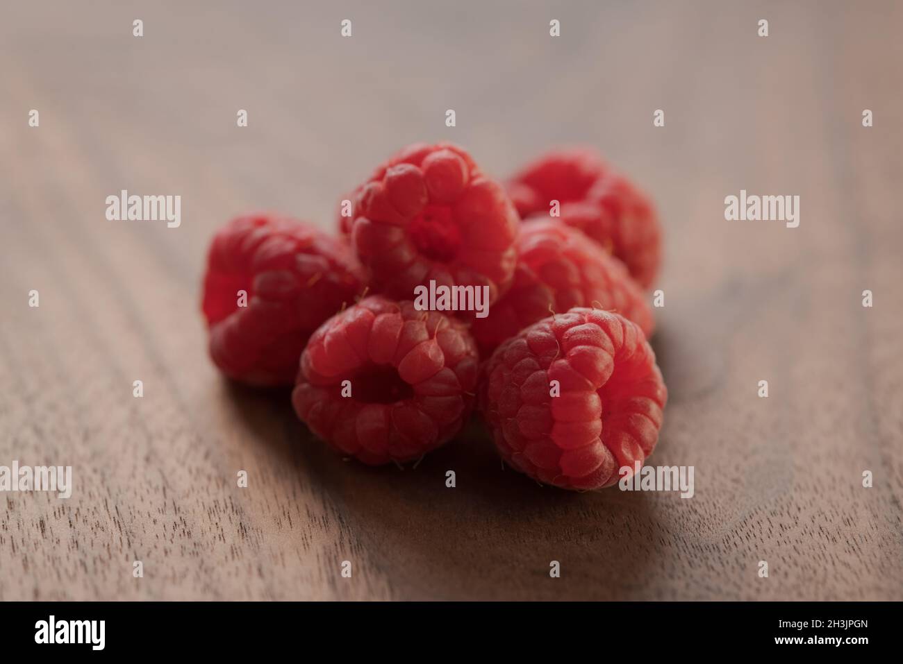 ripe raspberry on a walnut wood background, shallow focus Stock Photo