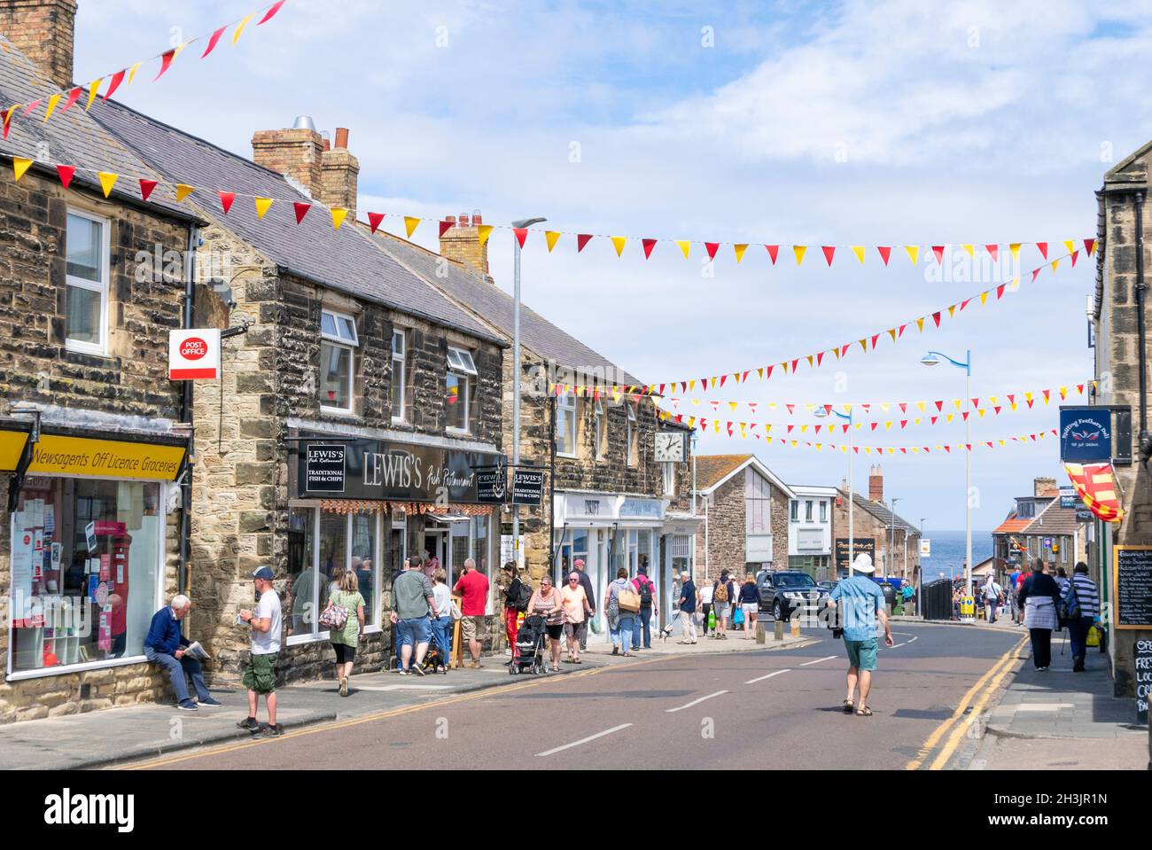 Tourists shopping in the Shops on the Main street decked in bunting through Seahouses Northumberland England UK GB Europe Stock Photo