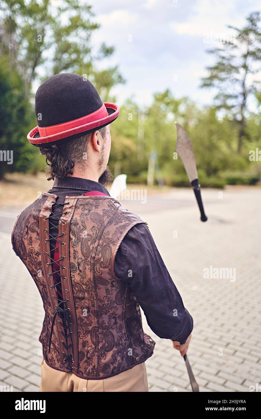Funny male performer juggling knives during show in the park Stock Photo