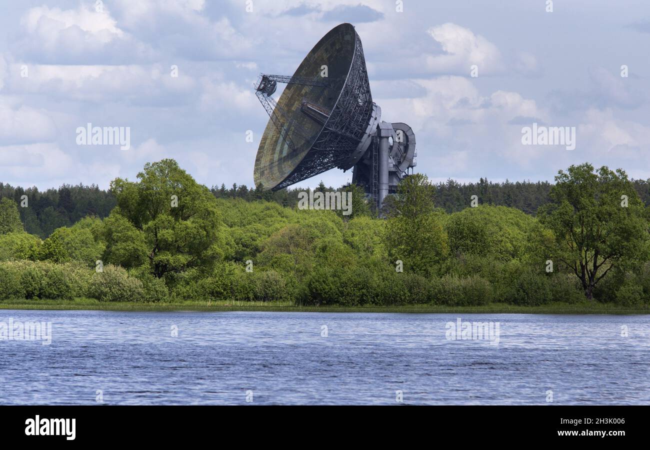 Huge satellite dish aimed at the sky, stands near river bank in Kaljazin, Russia. Stock Photo