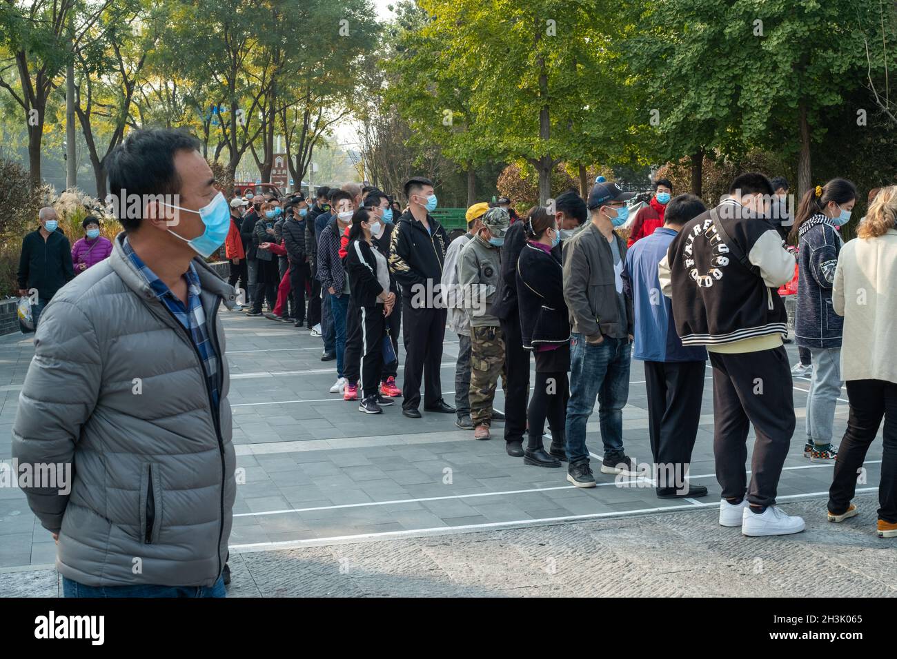 Residents line up to receive booster shots against COVID-19 at a vaccination site in Beijing, China. 29-Oct-2021 Stock Photo