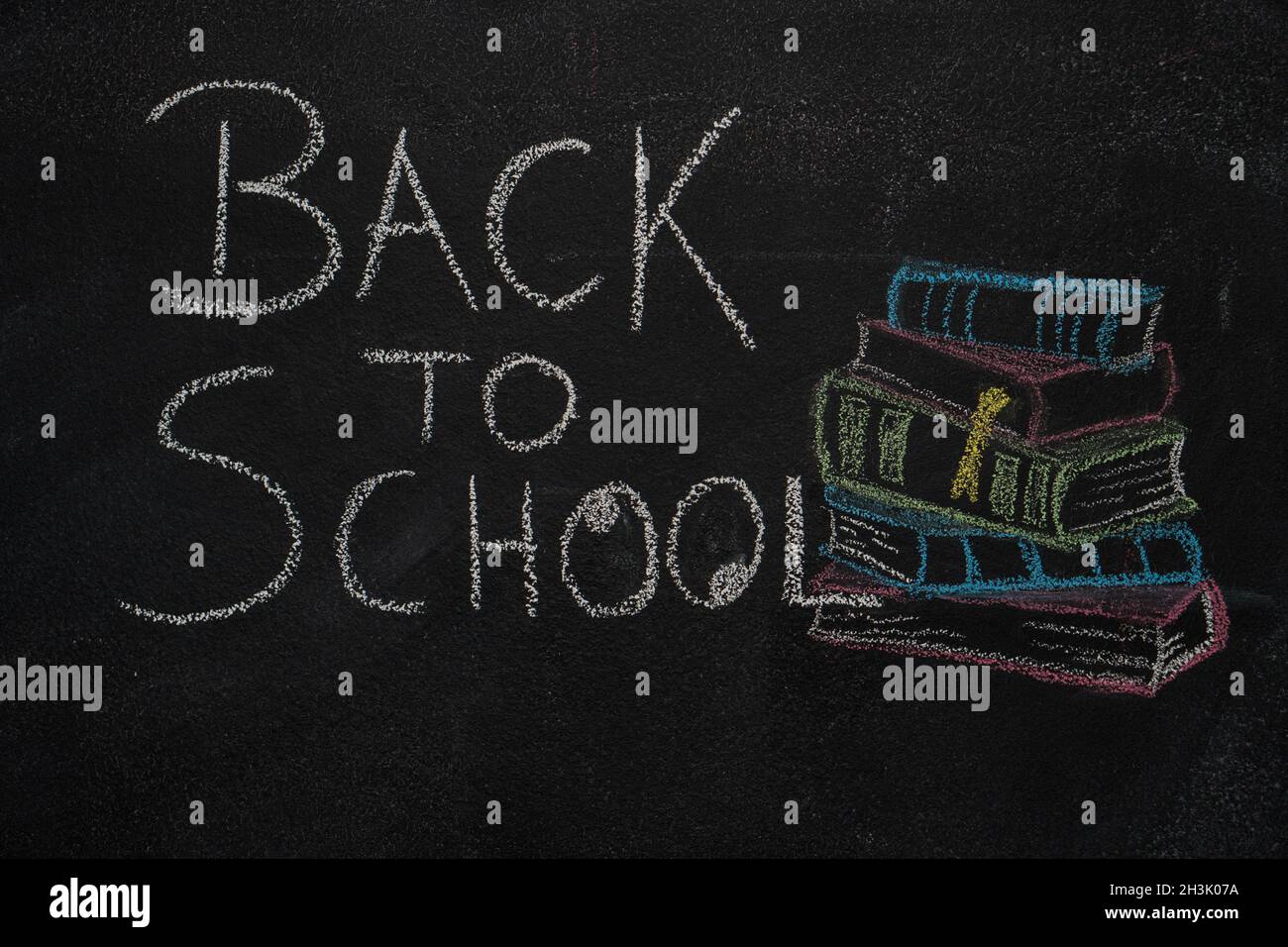 Back to school text and stack of books with apple drawn on black chalkboard Stock Photo