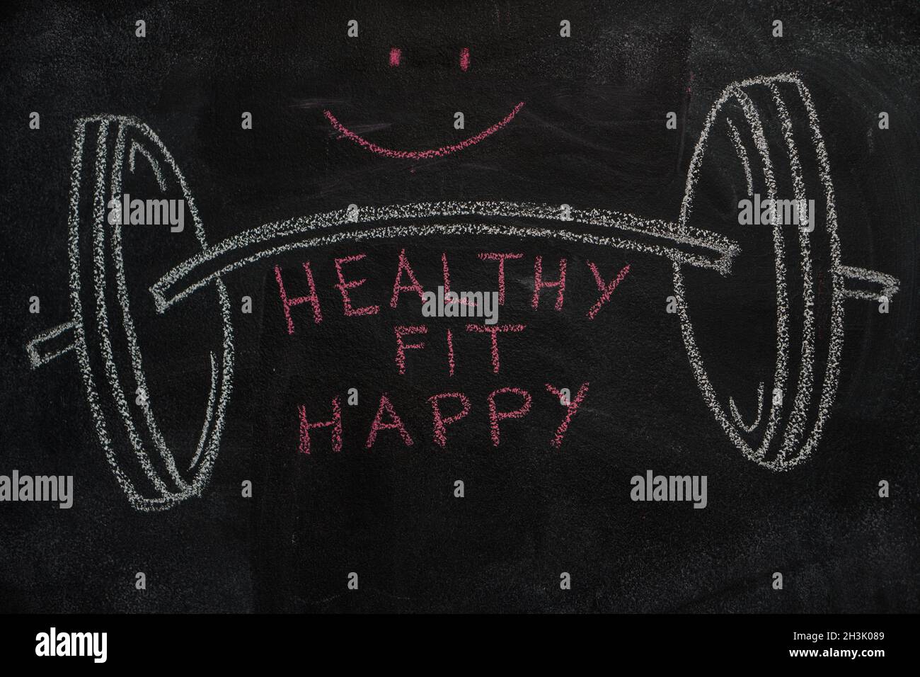 Barbell and healthy, fit, happy words on black chalkboard Stock Photo