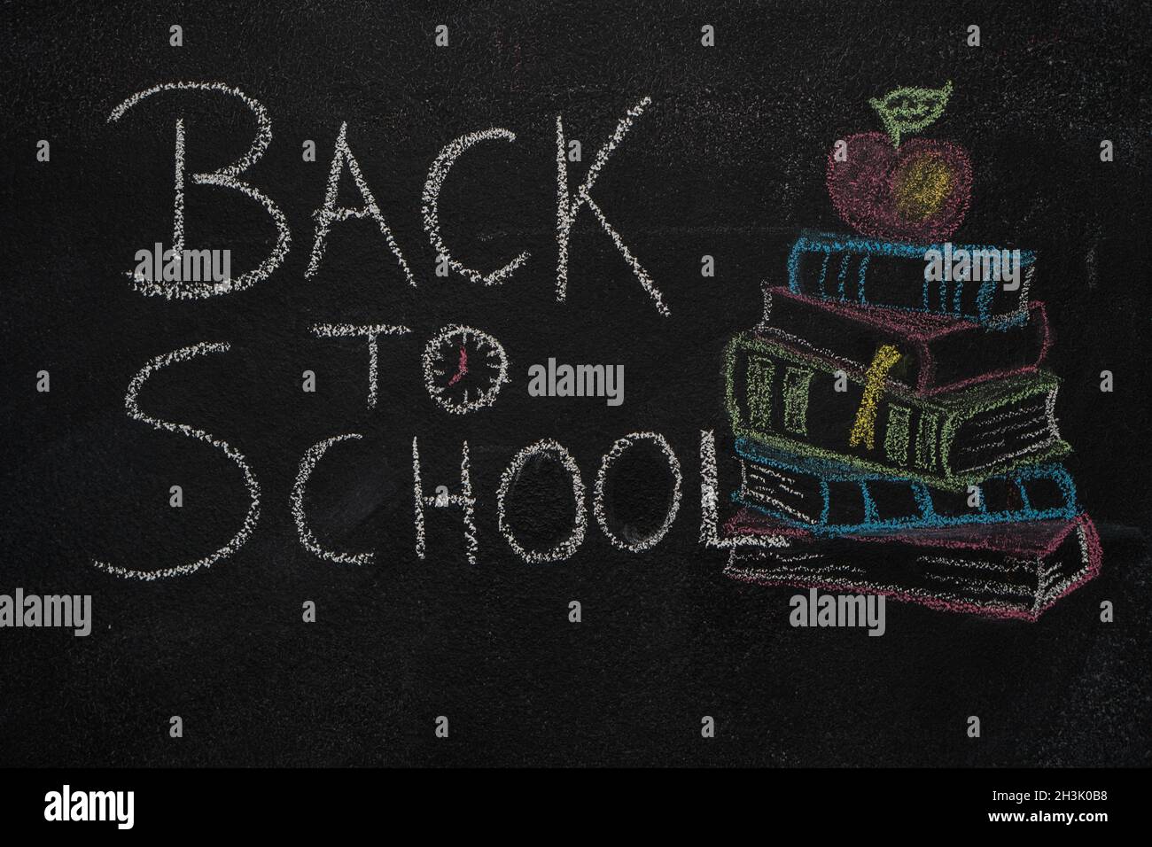 Back to school text and stack of books with apple drawn on black chalkboard Stock Photo