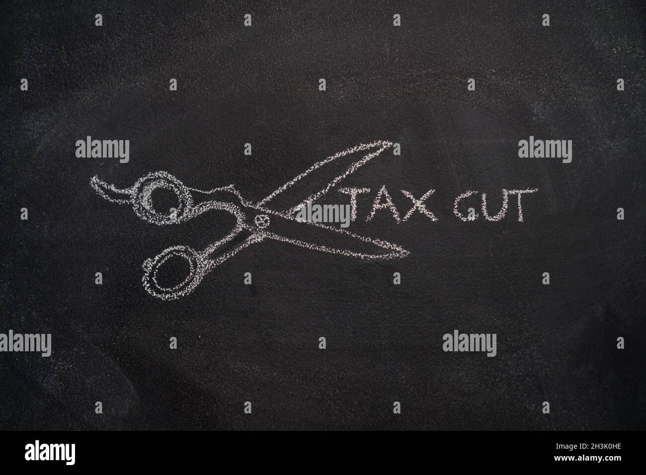 Scissors with tax cut writing on chalkboard Stock Photo