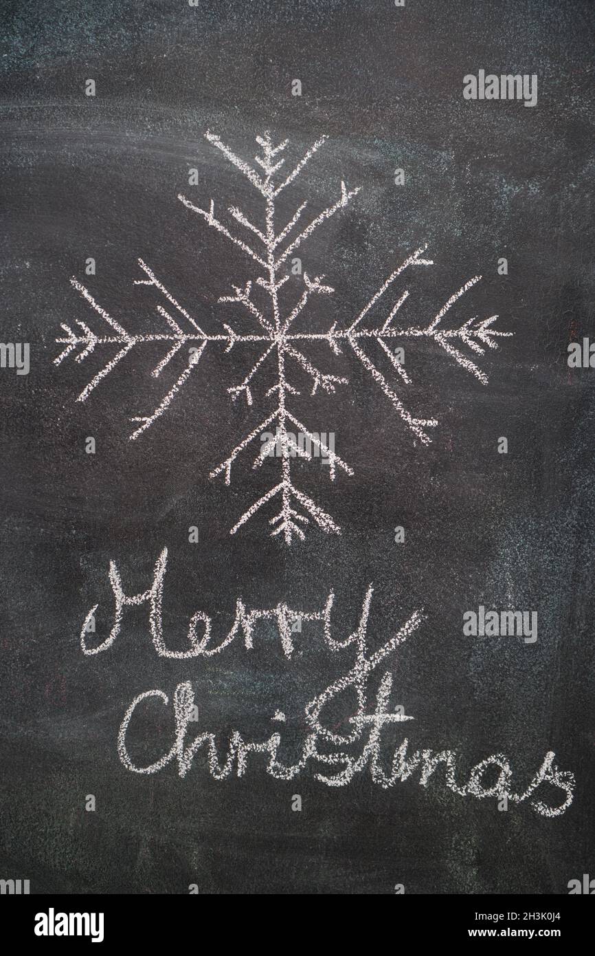 Big snowflake with Merry Cristmas writing on black chalkboard Stock Photo