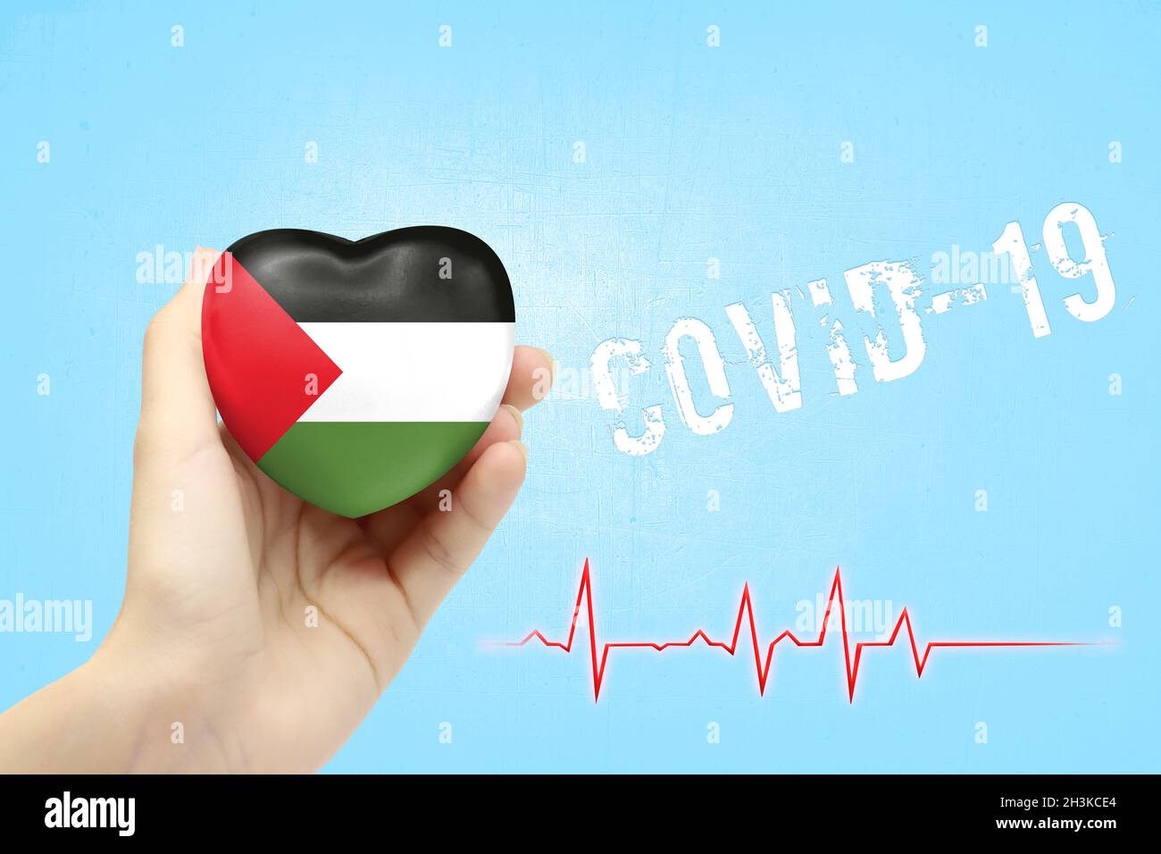 A girl is holding a toy in the shape of a heart with the flag of Palestine, a concept of health care during the covid-19 coronavirus pandemic Stock Photo