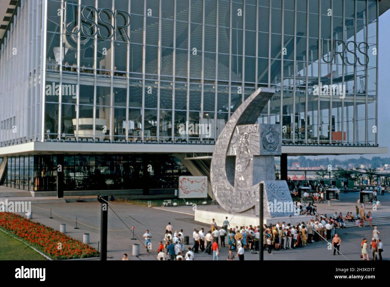 The USSR pavilion (Soviet Union, URSS or Moscow Pavilion) at Expo 67, Montreal, Quebec, Canada in 1967. It was designed by a team of architects led by Mikhail Posokhin. In front is a huge monumental sculpture of the symbol of Soviet Union, the hammer and the sickle. Since the 1990s the steel and glass pavilion has been best known as the Moscow Pavilion. This image is from an old amateur Kodak colour transparency – a vintage 1960s photograph. Stock Photo