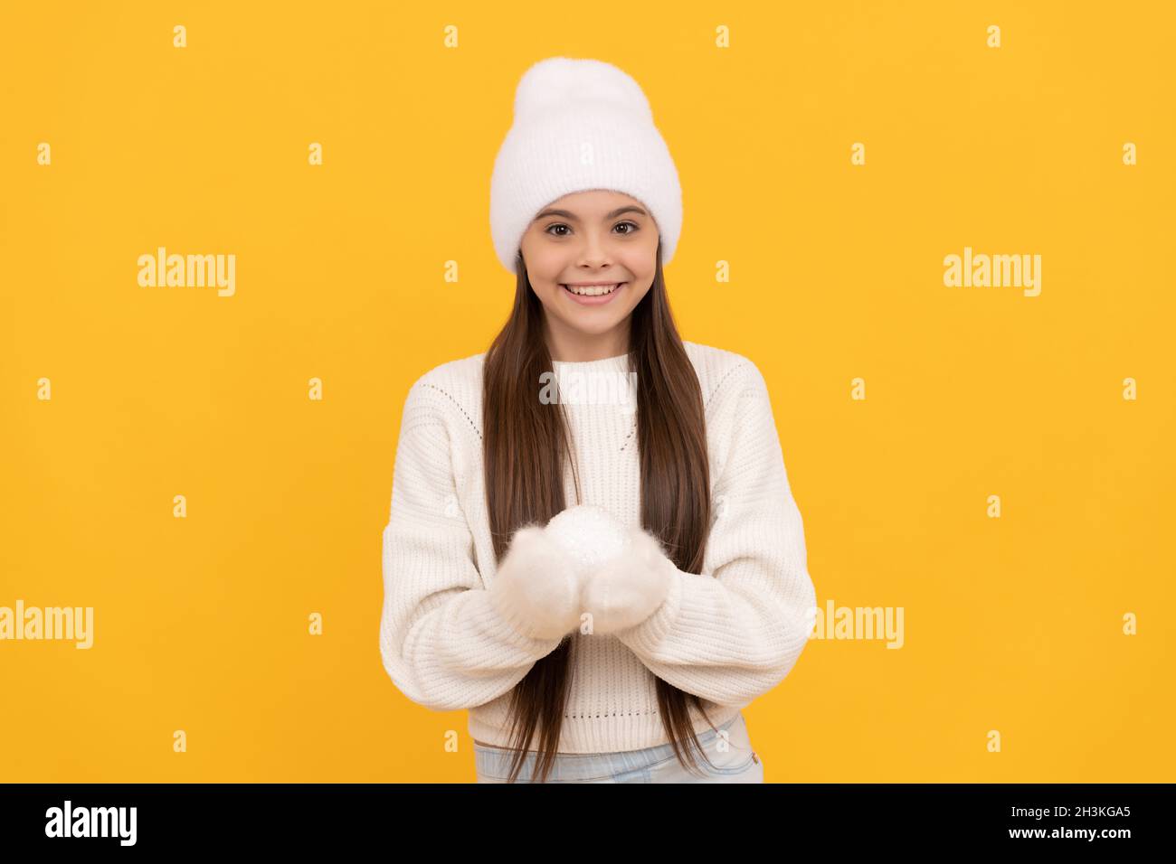 happy kid in winter hat and gloves hold snowball on yellow background, christmas Stock Photo