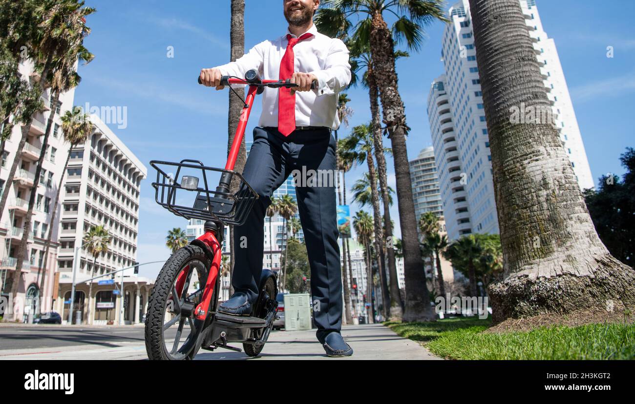 Happy manager in formalwear use e-scooter on street, urban lifestyle Stock Photo