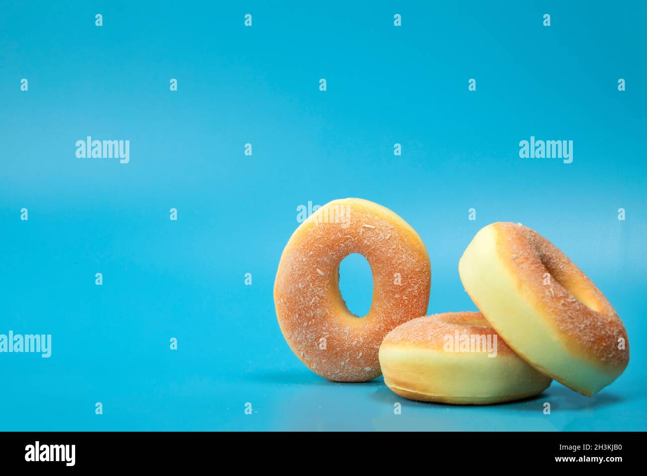 Pile with three simple donuts with sugar isolated on blue background ...