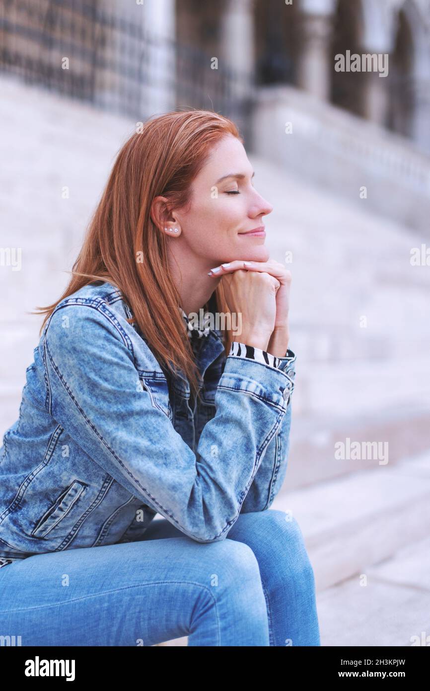 Caucasian redhead woman resting on stairs in city outdoors Stock Photo