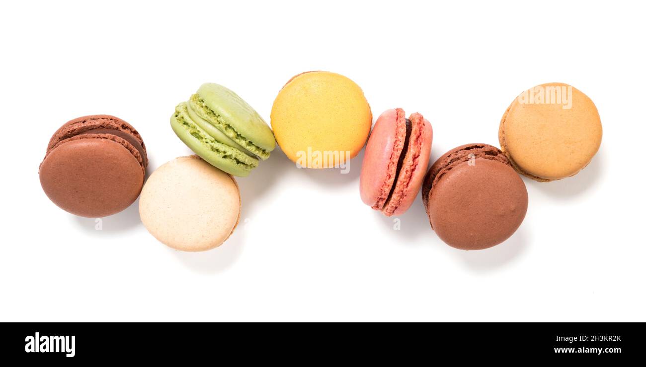 Variety of pastel colored macarons pastry, isolated on white background. High angle panoramic view of french cookies. Stock Photo
