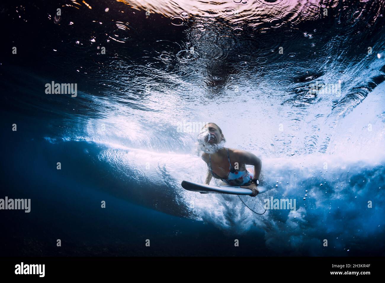 Surfer girl with surfboard dive underwater with under ocean wave Stock