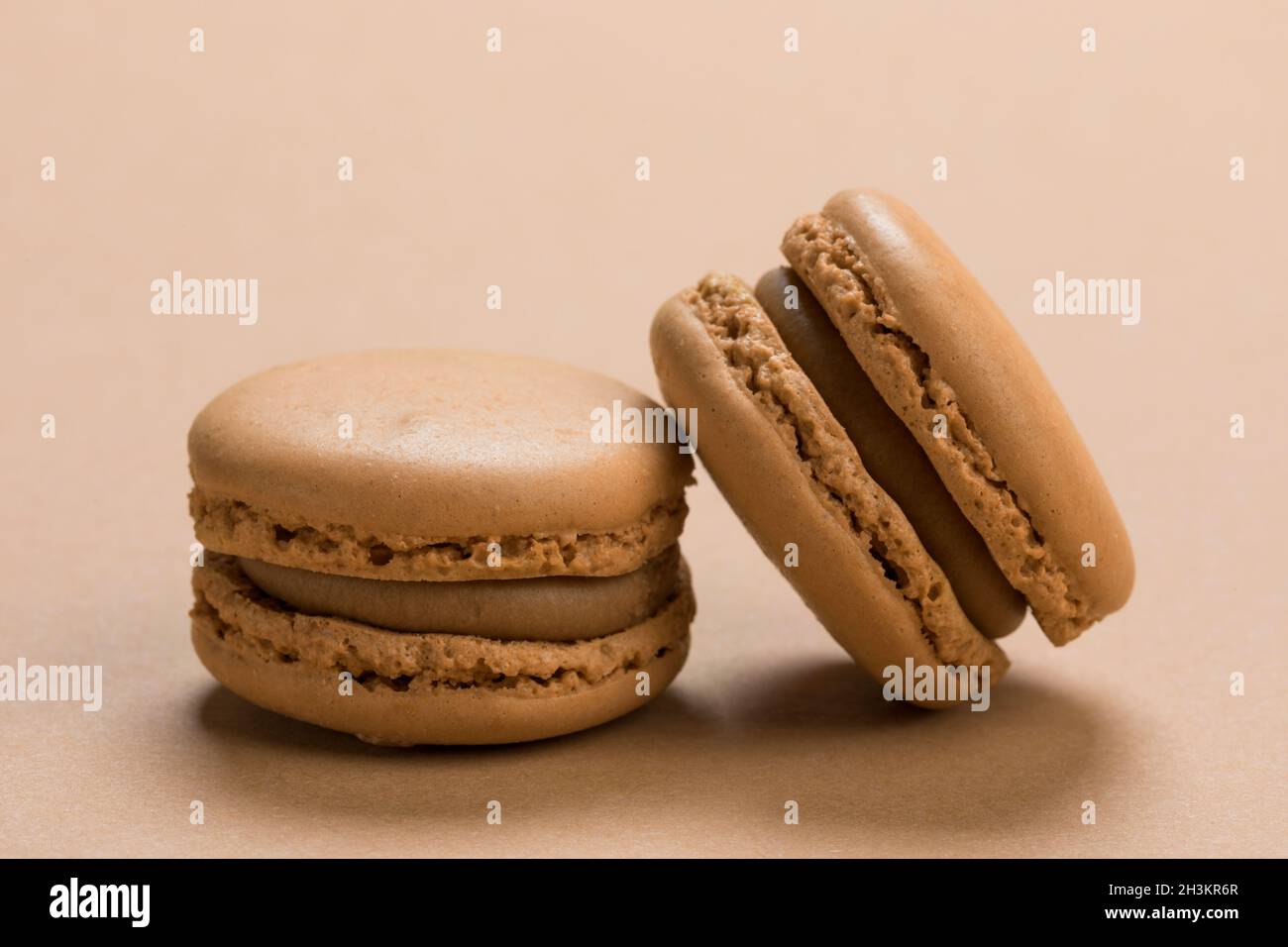 Coffee flavor French macaron cookies closeup on background of a similar light brown colour Stock Photo