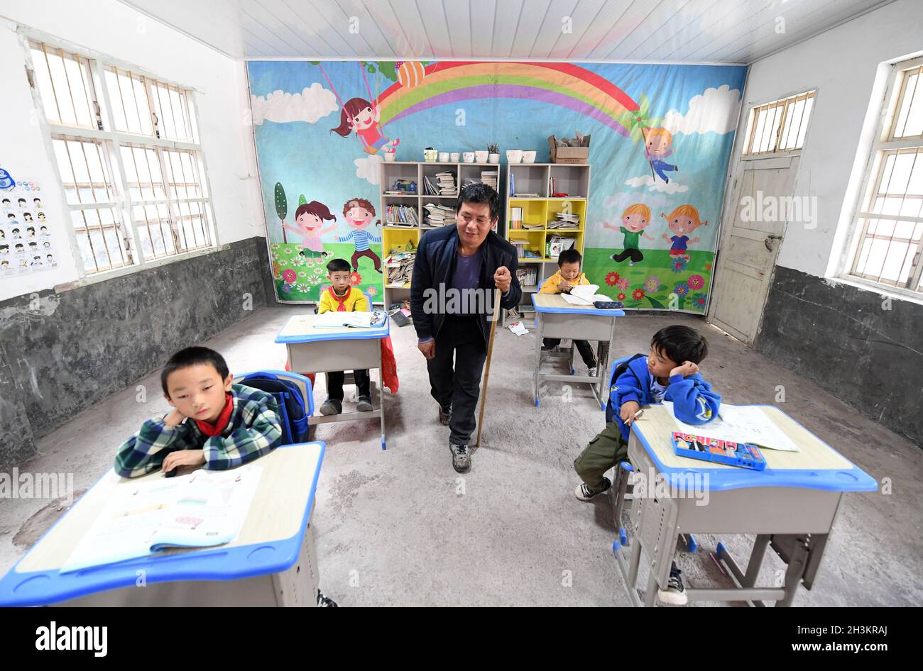 (211029) -- LINGCHUAN, Oct. 29, 2021 (Xinhua) -- Rural teacher Qin Xingguo teaches a lesson at a school in Haiyang Township, Lingchuan County, south China's Guangxi Zhuang Autonomous Region, Oct. 28, 2021.  Rural teacher Qin Xingguo works at the Antai teaching center in Haiyang Township.  For the past 27 years, Qin has dedicated himself to helping the children here realize their dreams through education.   As a toddler, Qin Xingguo's right foot was paralyzed due to polio. Since 1994, he has been teaching at three different places as far away as 15 kilometers from home. 'Because of my leg disab Stock Photo