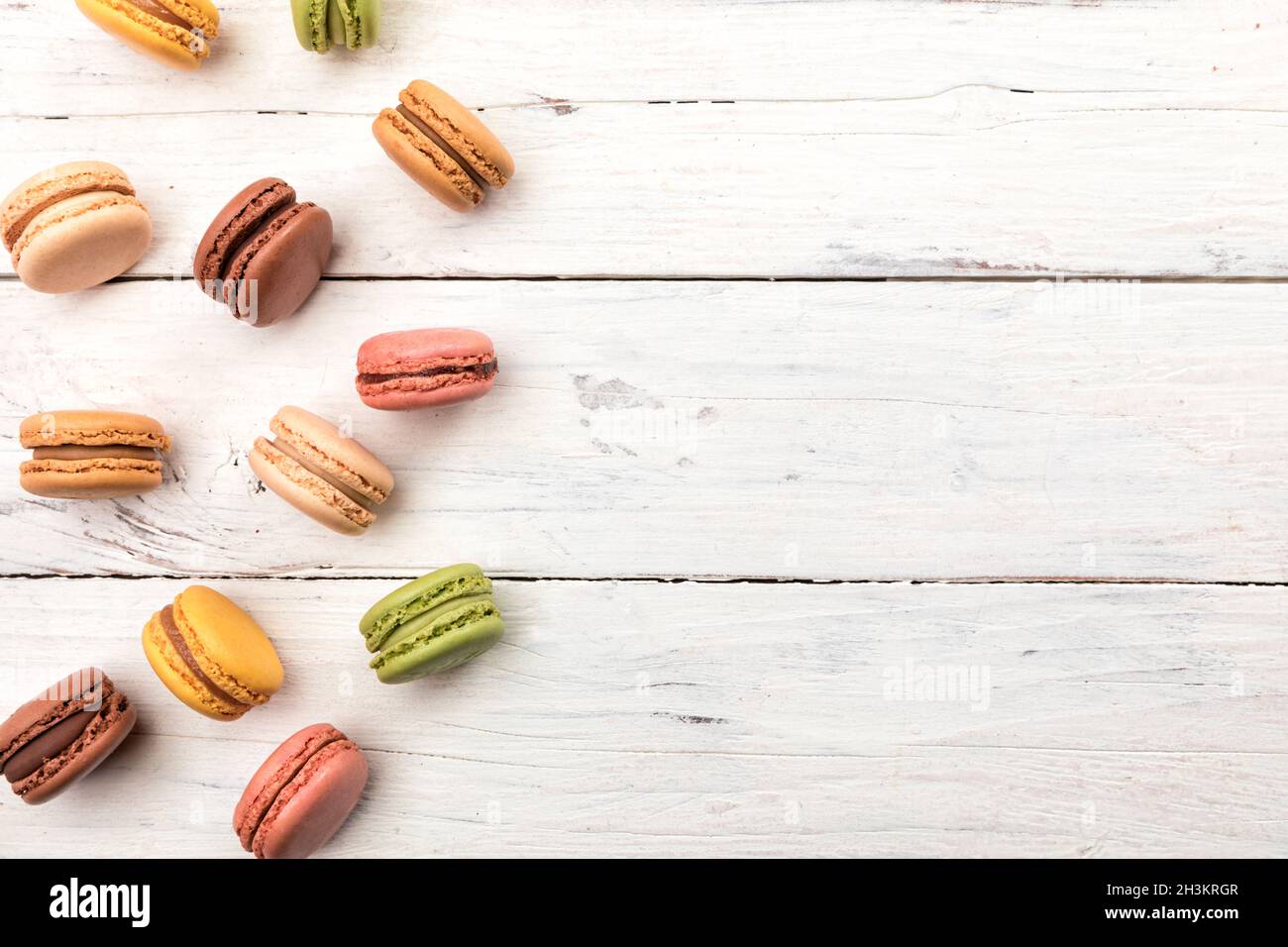 Rustic wooden background with a variety of colorful macarons pastry, French cookies high angle view with copy space Stock Photo