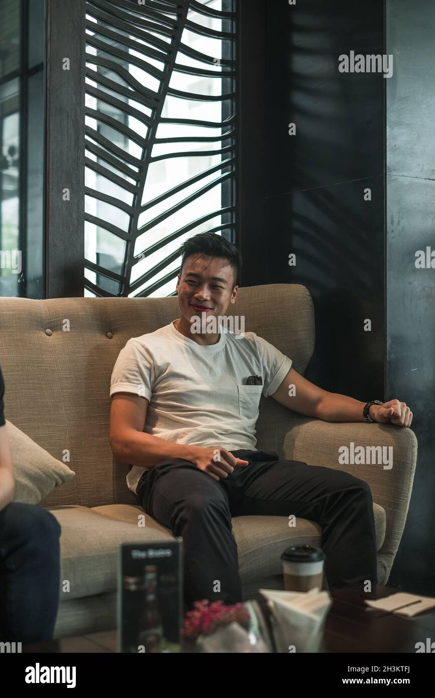 Asian young handsome man sitting in coffee shop, talking and smiling ...