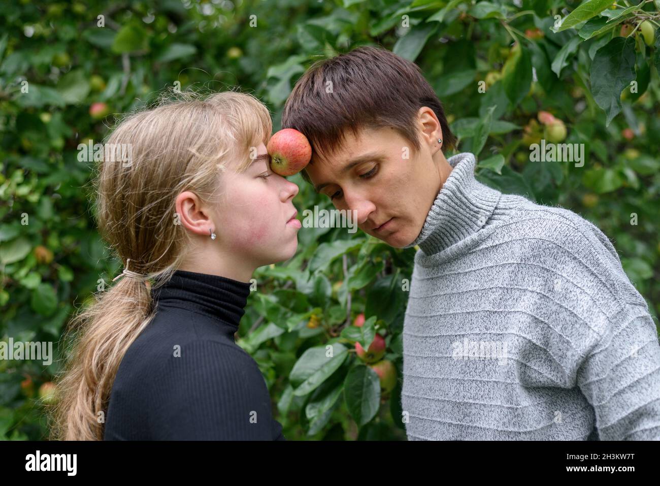 Two women holding an apple between foreheads during dance improvisation outdoors Stock Photo