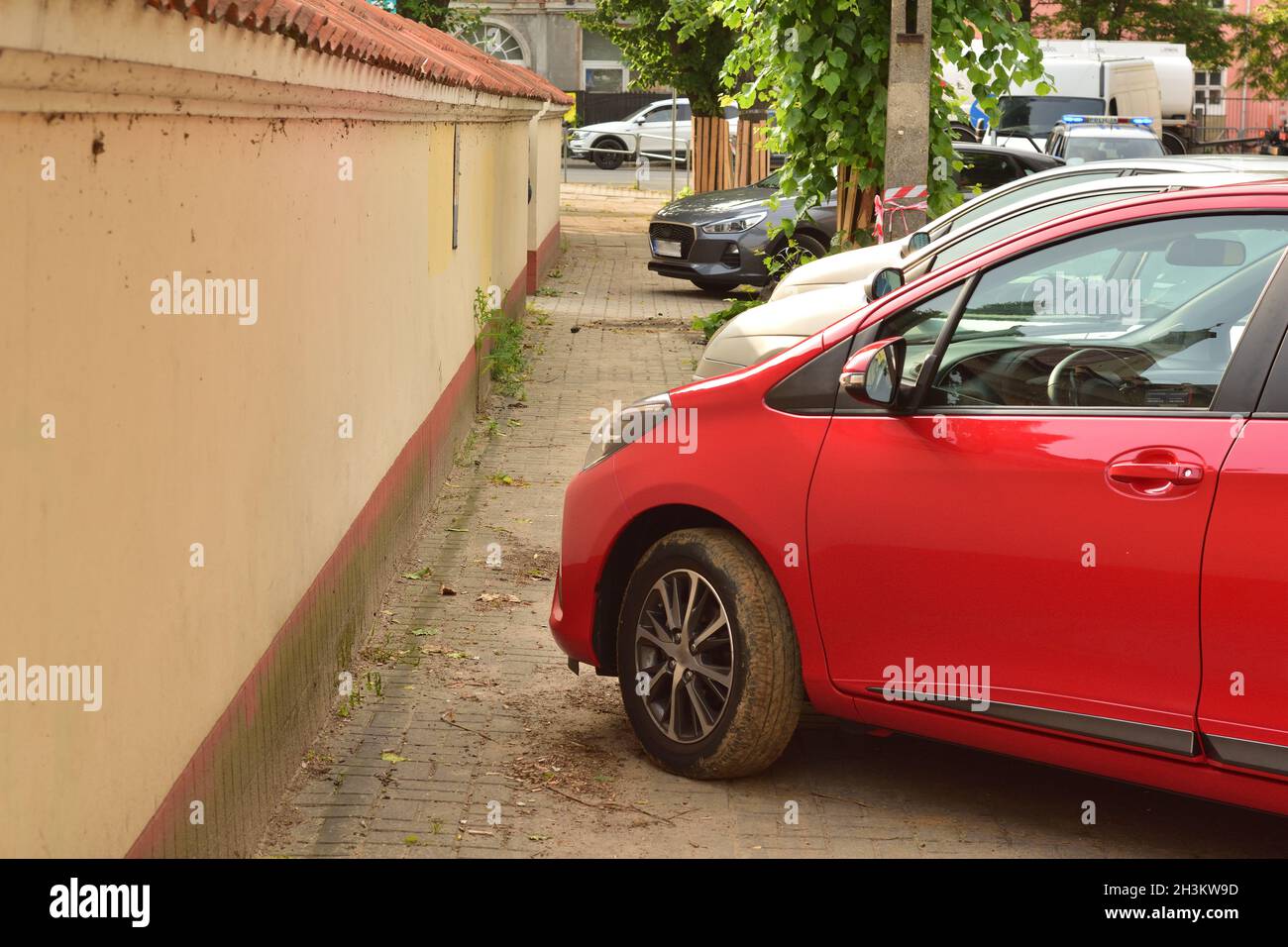 A passenger car standing on the sidewalk is blocking the pedestrian