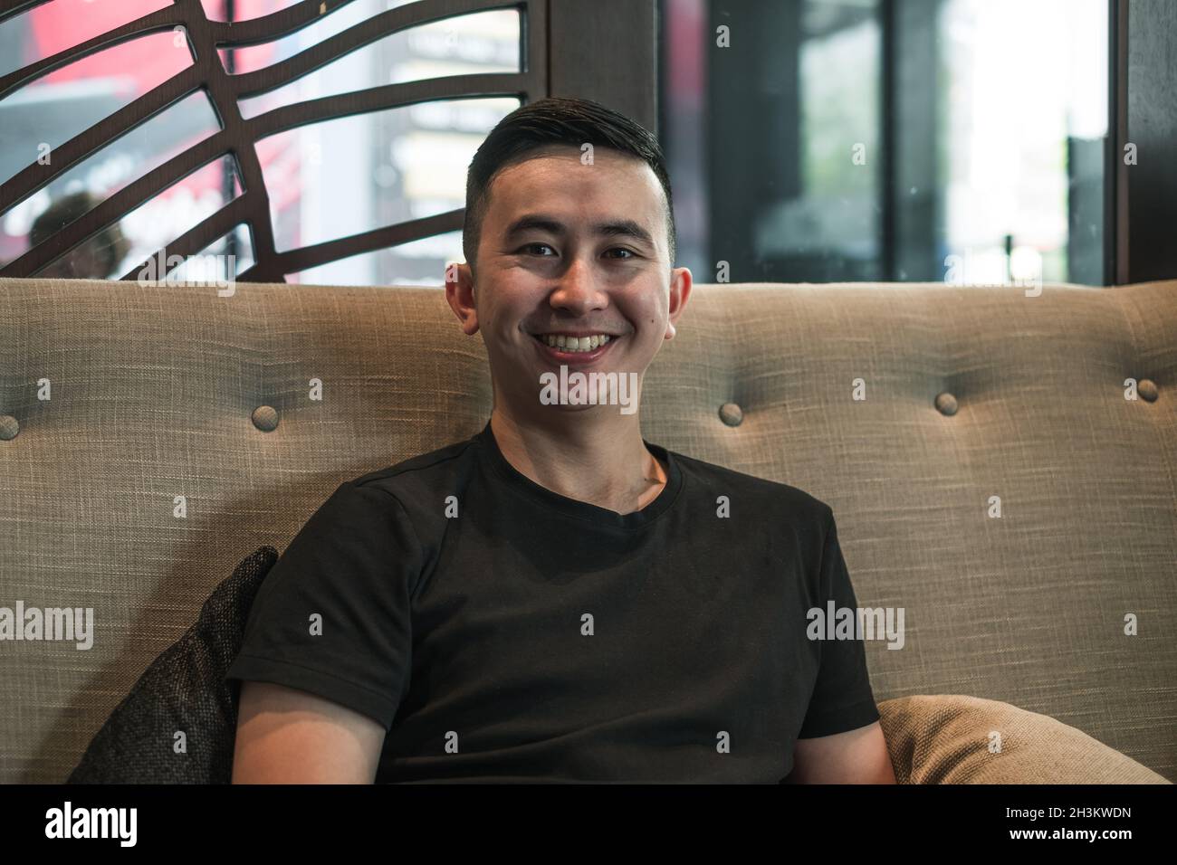 Portrait of asian young handsome man in black t-shirt sitting in coffee shop and smiling. Lovely smile, Happy person, millennials life, lifestyle Stock Photo