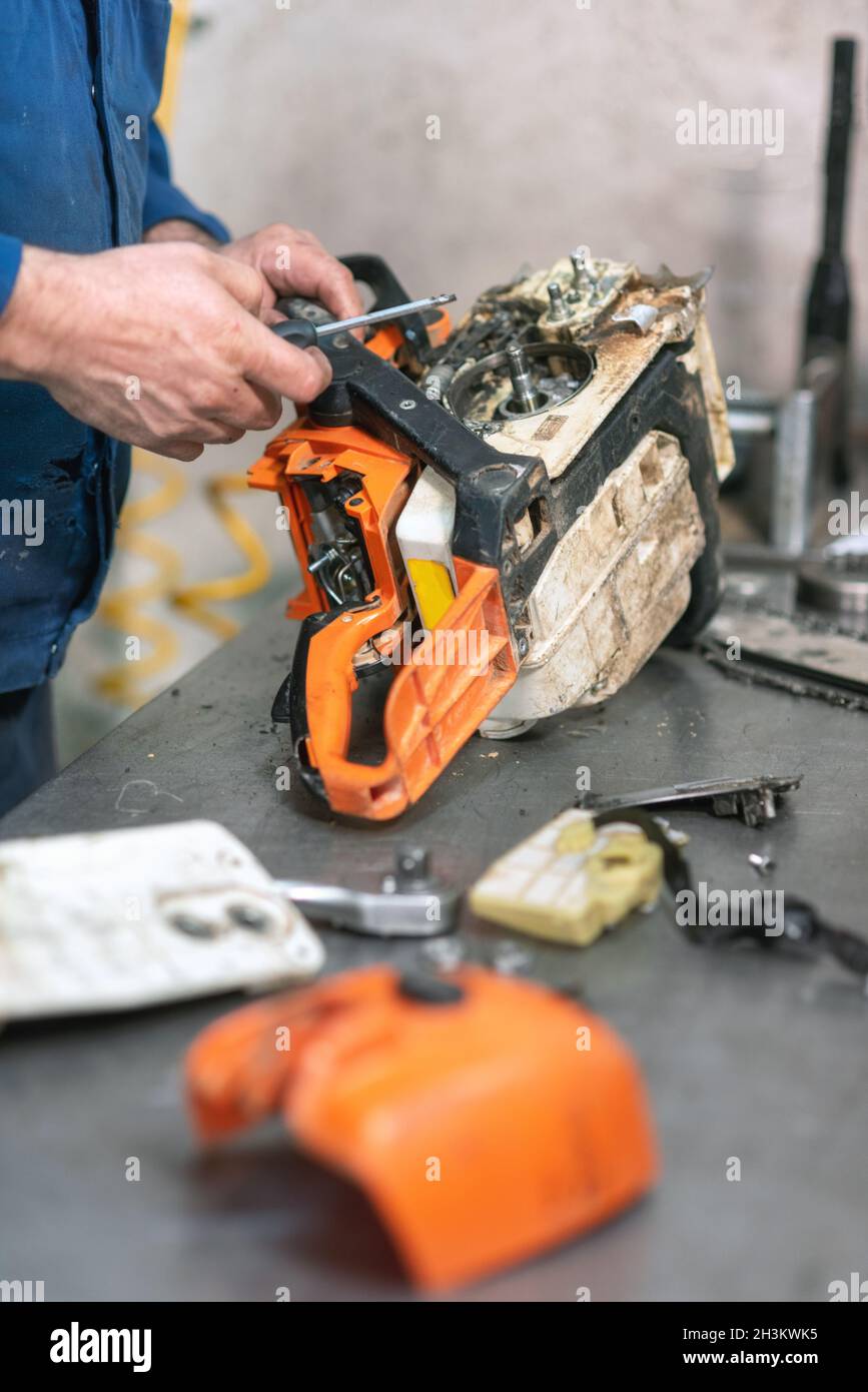Mechanic repairing a chainsaw. Man repairing a chainsaw in workbench
