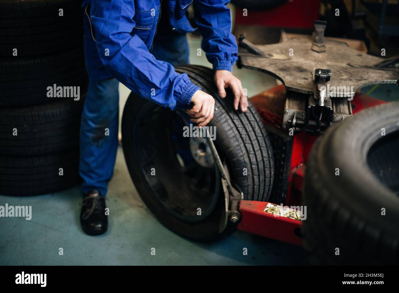 Auto mechanic balances the car wheel on the wheel balancer Stock Photo