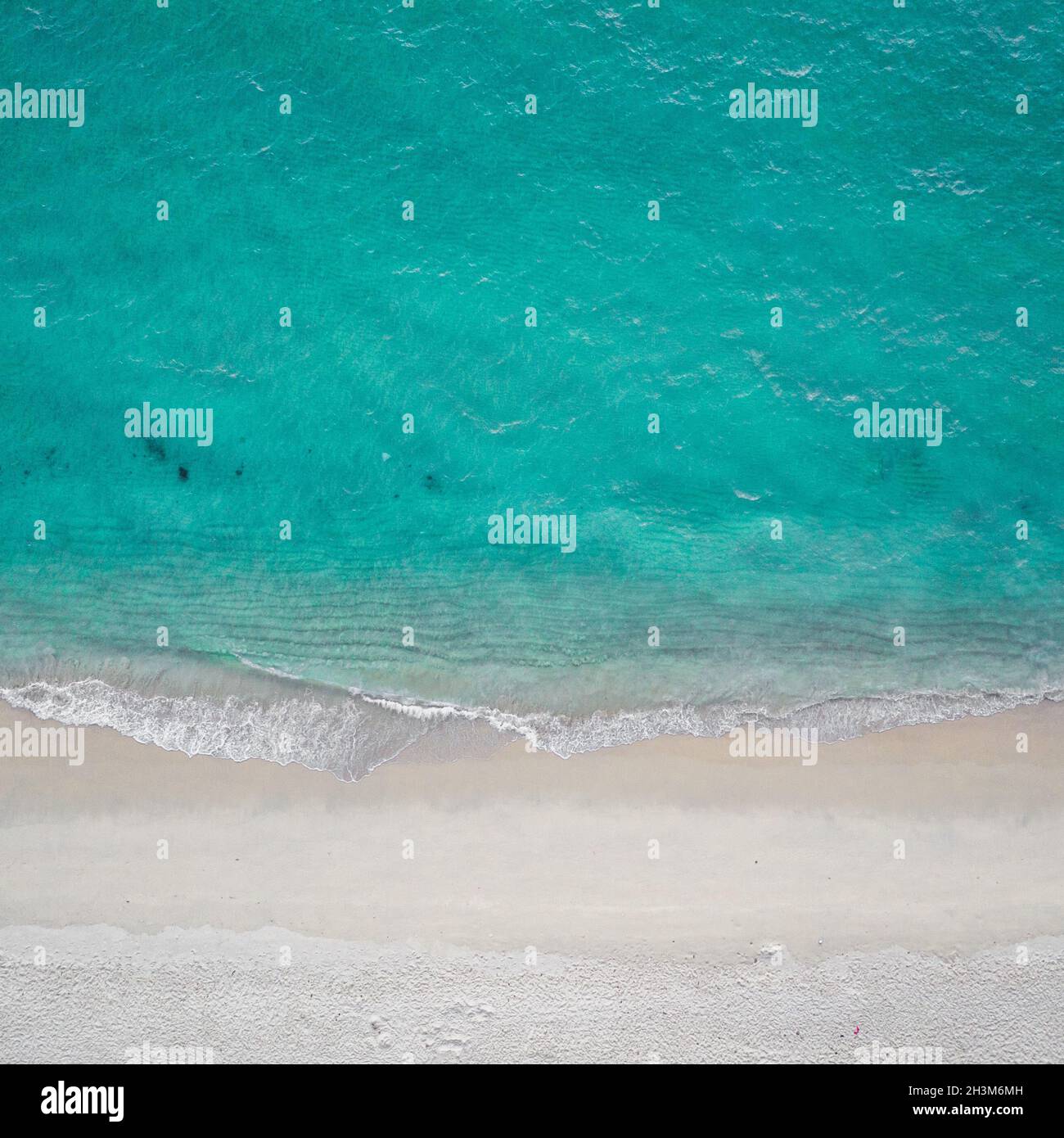Aerial top view of sea waves crashing against the sandy empty beach Stock Photo