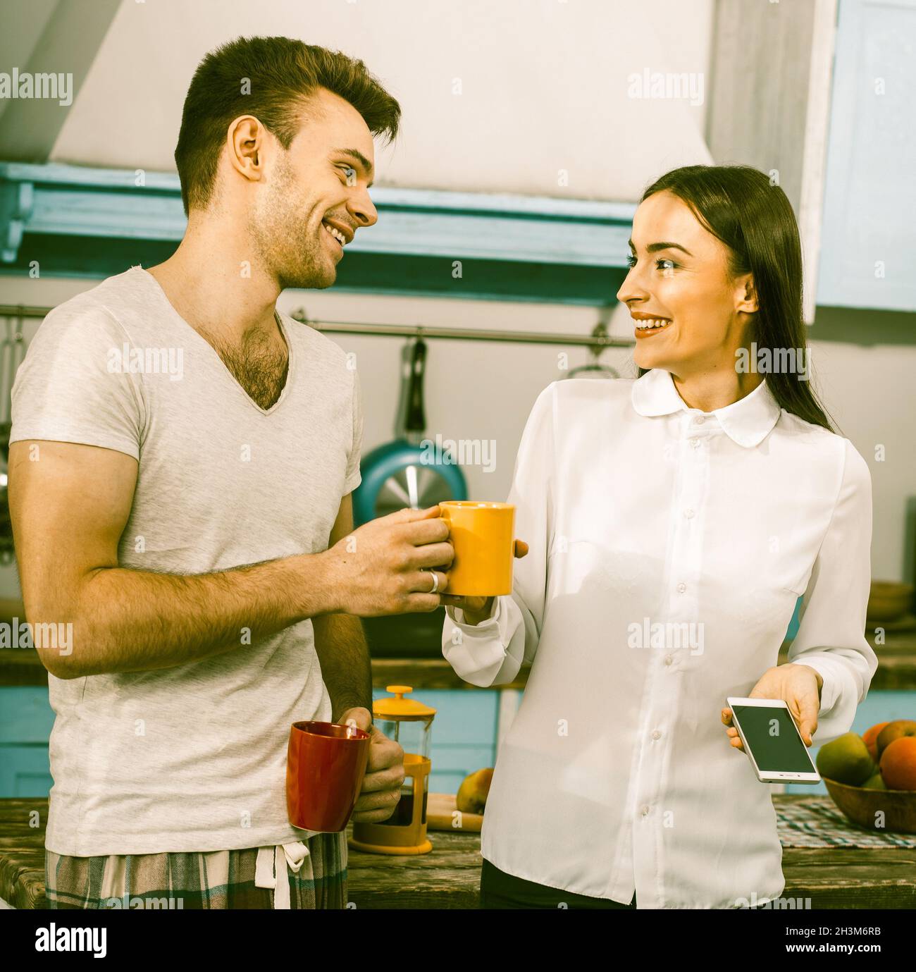 Business Woman With Her Husband In Pyjamas Laughs At Kitchen Stock Photo