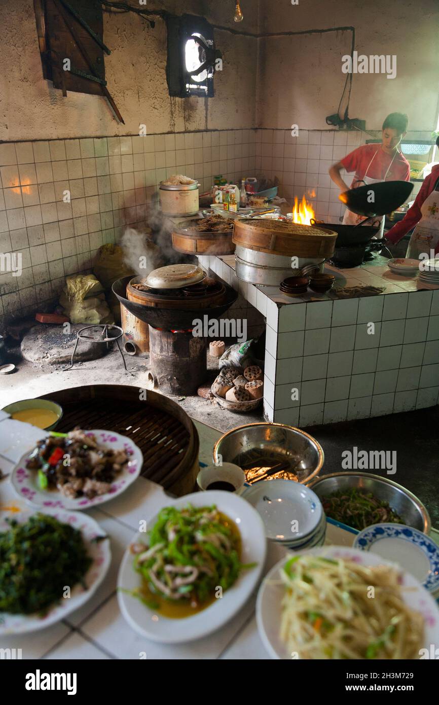Busy hot messy untidy local & cheap kitchen serving genuine ethnic Chinese cooking / cooked food meals / meal in Sichuan. China. (125) Stock Photo