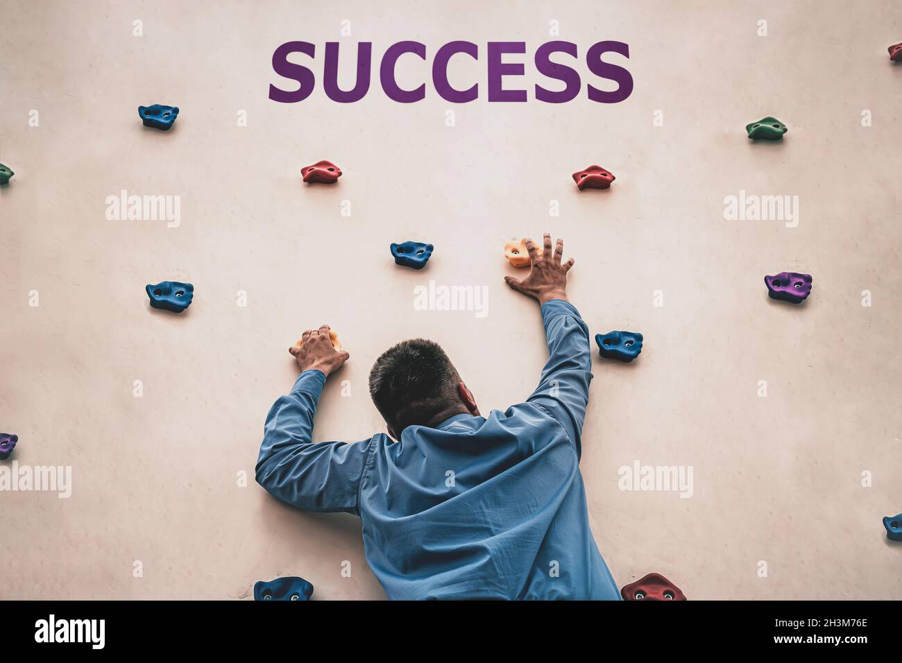 The concept of the difficulty of achieving success in business or career. A young man climbs the wall. Achieving success. career advancement. Stock Photo